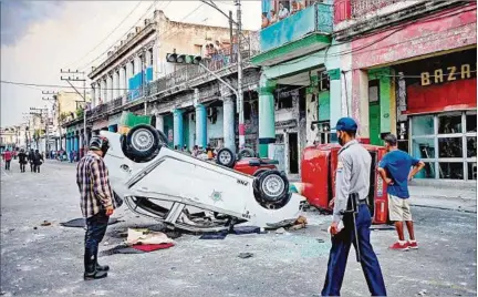  ??  ?? LA HABANA. Vehículos de la policía destrozado­s durante los enfrentami­entos del domingo; hasta ahora, solo se informó de un muerto.