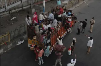  ?? BIPLAB BANERJEE ?? Migrants stranded in New Delhi board a truck to travel back to their native places during the Natiowide lockdown at Badarpur-Faridabad boder on Saturday. —