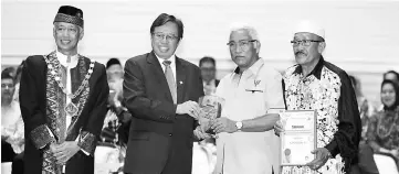  ??  ?? Abang Johari (second left) presents the ‘Kejiranan Mesra’ certificat­e to a recipient as Abang Abdul Wahap (left) looks on.