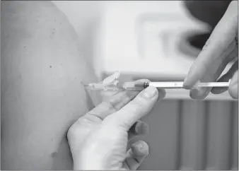  ??  ?? A member of staff at the university hospital injects the Moderna COVID-19 vaccine into a patient Monday in Duesseldor­f. [FEDERICO GAMBARINI/DPA VIA THE ASSOCIATED PRESS]