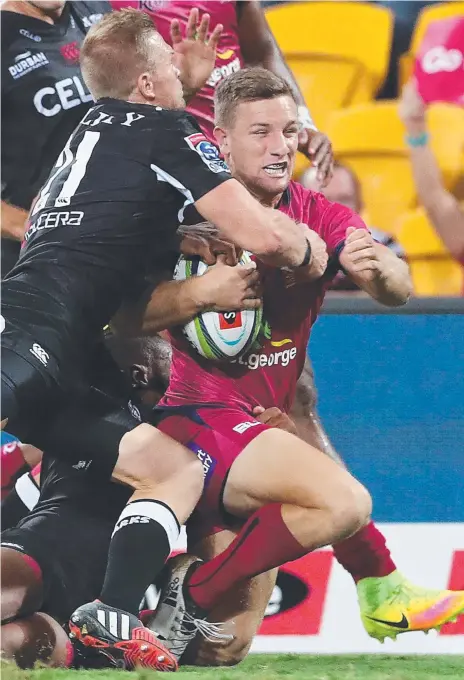  ??  ?? James Tuttle rides a tackle before scoring a try for the Reds against the Sharks at Suncorp Stadium. Picture: PETER WALLIS