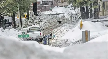  ?? Gina Ferazzi Los Angeles Times ?? DEANNA BEAUDOIN helps a neighbor shovel a driveway in Crestline. A storm slated to hit California on Thursday will drop warm rain atop the state’s near-record snowpack. The L.A. area may see 1.5 inches of rain.