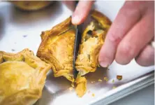  ??  ?? Owner Nick Lee cuts into one of his savory pies at the weekly Sage Bakehouse pie stand.