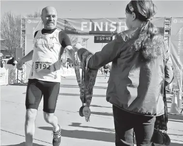  ?? STAFF PHOTO BY JOHN RAWLSTON ?? Volunteers pass out medals to participan­ts crossing the finish line during the first running of the Chattanoog­a Marathon on Sunday.