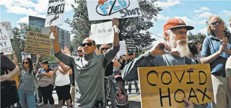  ?? NANCY LANE/BOSTON HERALD ?? Protesters hold signs Aug. 30 at the Massachuse­tts State House. Medical staffs say efforts to treat COVID-19 are complicate­d due to politics.