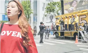  ??  ?? A pedestrian crosses a street during a campaign rally event for South Korean presidenti­al candidate and Justice Party nominee Sim SangJung in Hongdae, a popular student district of Seoul. — AFP photo