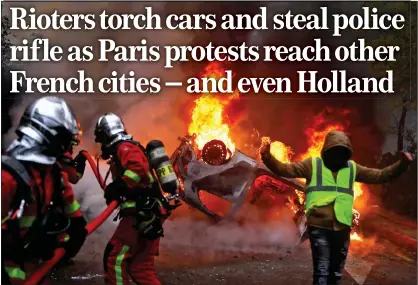  ??  ?? city in flames: A ‘yellow vest’ protester in Paris stands by as firefighte­rs attempt to douse a burning car