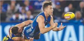  ??  ?? North Melbourne's Shaun Higgins handballs while tackled by Dayne Zorko.