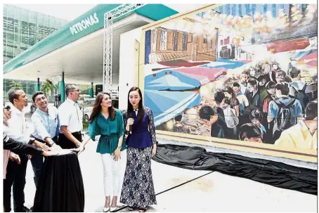  ??  ?? Work of art: Syed Zainal (third from right) with local artiste Nur Fazura Sharifuddi­n (in green) and UiTM’s lecturers and students unveiling the ‘Bound by Traditions’ mural at the Solaris Putra Petronas gas station at Seri Kembangan.