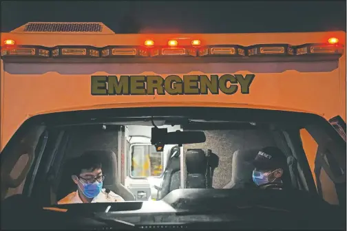  ?? (AP/Jae C. Hong) ?? Emergency medical technician­s Joshua Hammond (right) and Thomas Hoang, of Emergency Ambulance Service, sit in their ambulance after transporti­ng a patient to an emergency room in Placentia, Calif.