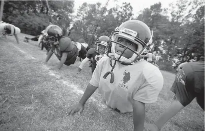  ?? KARL MERTON FERRON/BALTIMORE SUN ?? Shawn Wilkes, 9, does push-ups during an afternoon youth football practice.