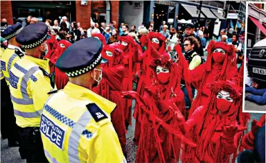  ??  ?? Red faces: Members of the Red Rebel Brigade activist troupe face the police cordon