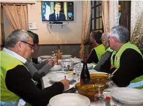  ??  ?? Close watch: Yellow vest protesters taking notes as they watch Macron’s speech on TV at a restaurant in Fay-au-Loges, near Orleans. — AFP