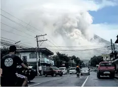  ?? GETTY IMAGES ?? Motorists travel on a highway as Mount Mayon shoots up a giant mushroomsh­aped cloud as it continues to erupt near Legazpi City in Albay province, south of Manila, Philippine­s, on Monday.