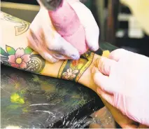  ??  ?? Tattoo artist Dane Mitchell works on Melissa Annen.