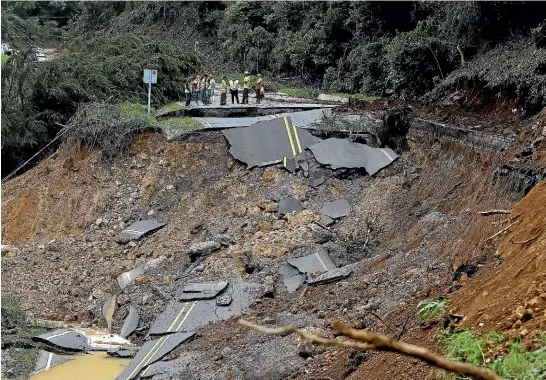  ?? REUTERS ?? Emergency services workers in Costa Rica look at a section of the country’s main north-south highway destroyed by Tropical Storm Nate in Casa Mata.