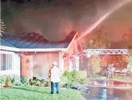  ?? MIKE JACHLES/BROWARD SHERIFF FIRE RESCUE/COURTESY ?? Firefighte­rs work to put out a blaze at a home in Cooper City late Sunday. The roof of the single-story house was partially collapsed and the facade was charred.