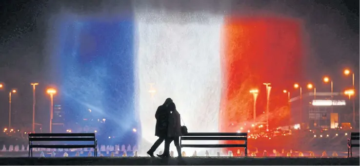  ?? AFP ?? A young couple in front of illuminate­d waters with the colours of the French national flag on Monday pay tribute to victims of the attacks claimed by the Islamic State which killed at least 129 people and left more than 350 injured on Friday night.