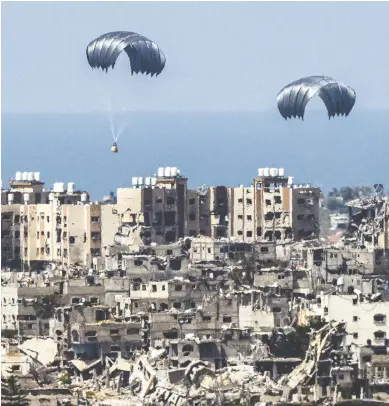  ?? JACK GUEZ / AFP VIA GETTY IMAGES ?? Airdrops of aid descend into Gaza, where the devastatio­n is apparent, but the exact death toll is in dispute.