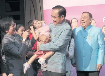  ?? CHANAT KATANYU ?? Bundle of trouble
Prime Minister Prayut Chan-o-cha holds a girl in his arms before attending a cabinet meeting which announced a package of New Year’s gifts for the people, including free use of motorways during the festive period and discounted air tickets.