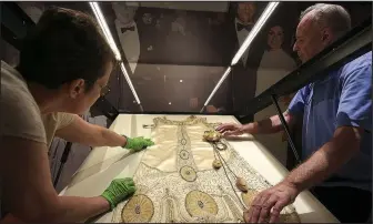  ?? File Photo/STATON BREIDENTHA­L ?? Curator Jo Maack (left) and conservato­r Harold Mailand with Textile Conservati­on Services work placing the gown of First Lady Eula Terral in a case in preparatio­n for the opening of “First Ladies of Arkansas: Women of Their Times” exhibit. The exhibit opens Sept. 14.