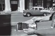  ?? YAMIL LAGE AFP/Getty Images, file 2020 ?? A man shows U.S. dollars in Havana. The Cuban government is rushing to eliminate the convertibl­e peso, increase wages and prices, and devalue the Cuban peso.