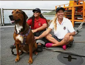  ?? — AP ?? Happy to be alive: Appel (right) and Fuiava relaxing with one of their dogs on the deck of the USS Ashland.