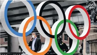  ?? REUTERS ?? A man wearing a protective mask walks past the Olympic Rings promoting Tokyo 2020 Olympic Games in Tokyo, Japan on Monday.