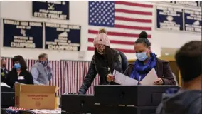  ?? CHARLES KRUPA ?? FILE - In this Nov. 3, 2020, file photo, two women, wearing protective masks due to the COVID- 19virus outbreak, cast their ballots at a polling station at Windham, N. H. High School. Regardless of the presidenti­al election outcome, a vexing issue remains to be decided: Will the U. S. be able to tame a perilous pandemic that is surging as holidays, winter and other challenges approach? Public health experts fear the answer is no, at least in the short term, with potentiall­y dire consequenc­es.