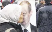  ??  ?? A Syrian woman kisses a poster of Russian President Vladimir Putin in Damascus in 2012. Russia began its air campaign in Syria on Sept. 30 , joining the fray at a critical time for President Bashar Assad and his embattled troops.