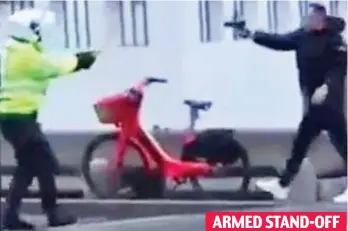  ?? ?? ARMED STAND-OFF
Brave: A police officer with a Taser confronts a suspect aiming a gun at his face