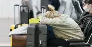  ?? ALEX BRANDON — THE ASSOCIATED PRESS ?? Jessica Andrijausk­as, from Buenos Aires, rests her head on her luggage as she awaits the results of her COVID-19 test, at Ronald Reagan Washington National Airport, Wednesday, Dec. 29, 2021, in Arlington, Va.