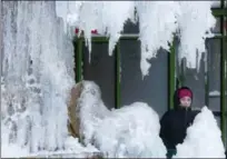  ?? MARK LENNIHAN — THE ASSOCIATED PRESS ?? A woman passes an ice-covered fountain in New York’s Bryant Park, Friday, Jan. 5, 2018. Frigid temperatur­es, some that could feel as cold as minus 30 degrees, moved across the East Coast on Friday as the region attempted to clean up from a massive...