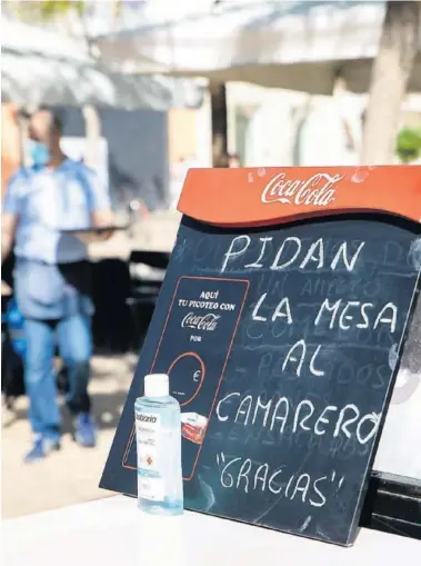  ??  ?? Un cartel de un bar junto a un bote de gel. Las ciudades en Fase 1 pueden disfrutar de las terrazas.