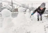  ?? BARRY GRAY THE HAMILTON SPECTATOR ?? Fan Xiao Man works on her quartet of snowmen in the front yard of a home on Whitney Avenue.