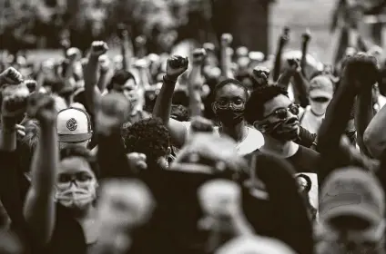  ?? Marie D. De Jesús / Staff photograph­er ?? People raise their fists in solidarity with George Floyd’s family in a June 2 march at Discovery Green.