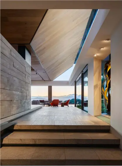  ??  ?? The entrance vista articulate­d on several floor levels, a powerfully structured ceiling and stone, concrete and wood Textures created a compelling arrival space opposite page dining and kitchen areas with The inverted pyramid ceiling showing lions head Through The glass clerestory