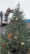  ??  ?? In luftiger Höhe werden die Christbaum­kugeln am großen Weihnachts­baum auf dem St. Johanner Markt befestigt.