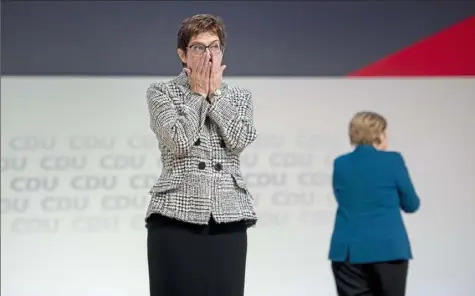  ?? Thomas Lohnes/Getty Images ?? Annegret Kramp-Karrenbaue­r reacts Friday after receiving the most votes to become the next leader of the German Christian Democrats (CDU) while Angela Merkel walks to the back at a federal congress of the CDU in Hamburg, Germany.