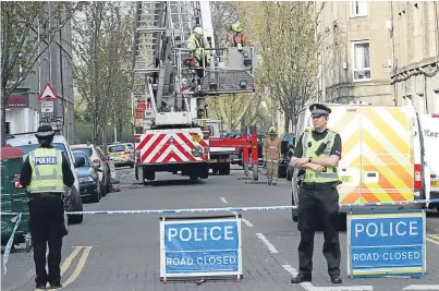  ??  ?? Fire and Rescue Service officers check the chimney of a flat on Park Avenue in Dundee after a blaze which led to a man being taken to hospital and evacuation of the block.