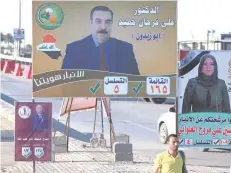  ?? — AFP ?? A man walks past posters of candidates for legislativ­e elections in Ramadi.