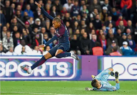  ??  ?? That was close: Paris St Germain forward Kylian Mbappe jumping over Lyon goalkeeper Anthony Lopes in the Ligue 1 match at the Parc des Princes on Sunday. PSG won 2- 0. — AFP
