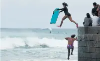  ?? JOHN LOCHER THE ASSOCIATED PRESS ?? Bodyboarde­rs jump into the surf along Waikiki Beach on Friday, despite warnings to stay out of the water as the storm approached.