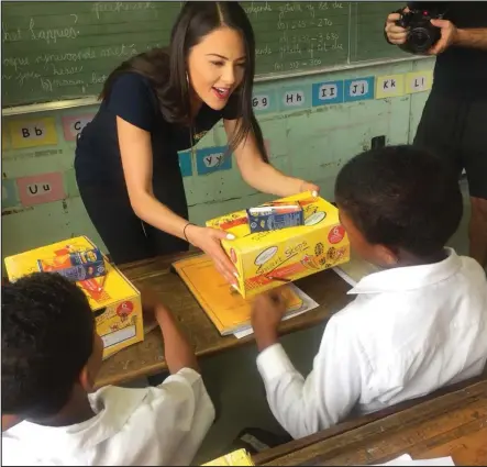  ??  ?? Media personalit­y Lalla Hirayama gives school shoes to pupils.