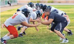  ?? JIM THOMPSON/JOURNAL ?? Mission Achievemen­t and Success football coach Elijah Langston works with his linemen as they prepare for Saturday’s game at Cobre.