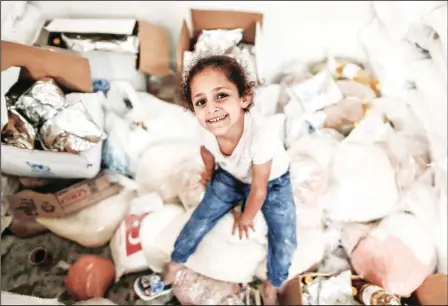  ?? (AFP) ?? A Palestinia­n girl smiles as she waits to receive aid at a United Nations food distributi­on centre in Jabalia refugee camp in the northern Gaza Strip on Aug8.