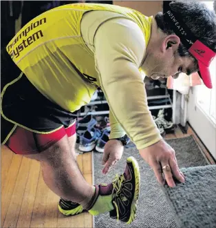  ?? AP PHOTO ?? Marathoner John Young puts on his running shoes before a training session in Salem, Mass.