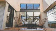  ?? ?? Double-stacked windows in the living room look out on to a deck that is open to the sky to allow views of greenery and branches overhead.