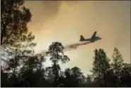  ?? NOAH BERGER — THE ASSOCIATED PRESS ?? A plane drops retardant while battling a wildfire near Oroville on Saturday. The fire south of Oroville was one of more than a dozen burning in the state as firefighte­rs worked in scorching temperatur­es to control unruly flames.