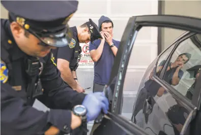  ?? Jessica Christian / The Chronicle ?? Mission District police Officer Robert Clendenen (left) attempts to lift fingerprin­ts while Officer Paul Lujano interviews Michael Lech after his car was broken into last month near Potrero Street and 24th Avenue.